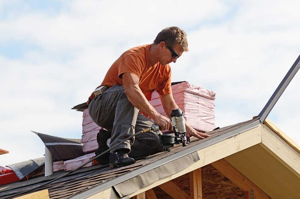 Roofing inspector examining a roof shingle label and layered roof assembly diagram.